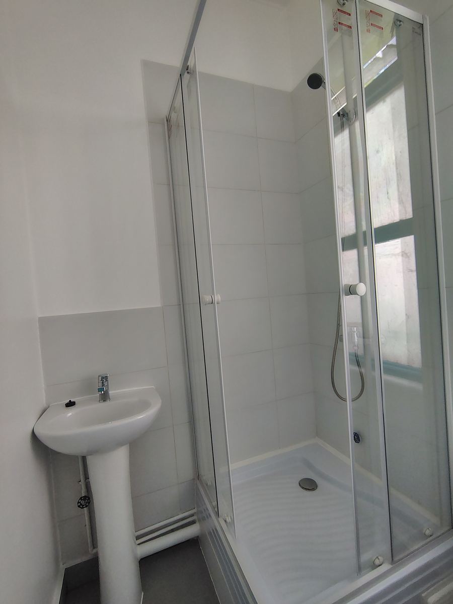 Baño terminado con lavamanos de pedestal y ducha con mampara